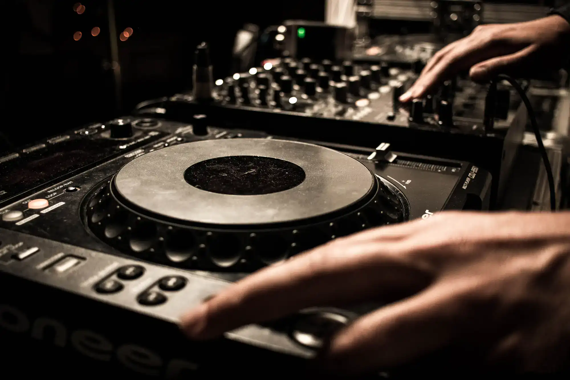A wedding DJ in Minnesota and Wisconsin adjusts a mixer and turntable during an event close-up.