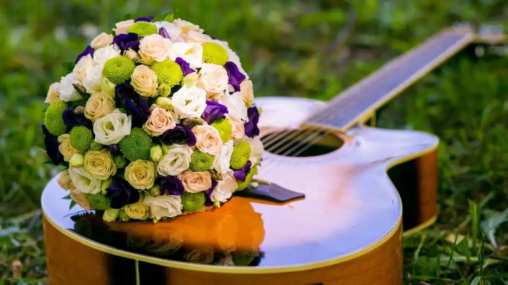 A vibrant bouquet of flowers rests on an acoustic guitar, suitable for a wedding DJ Minnesota event.