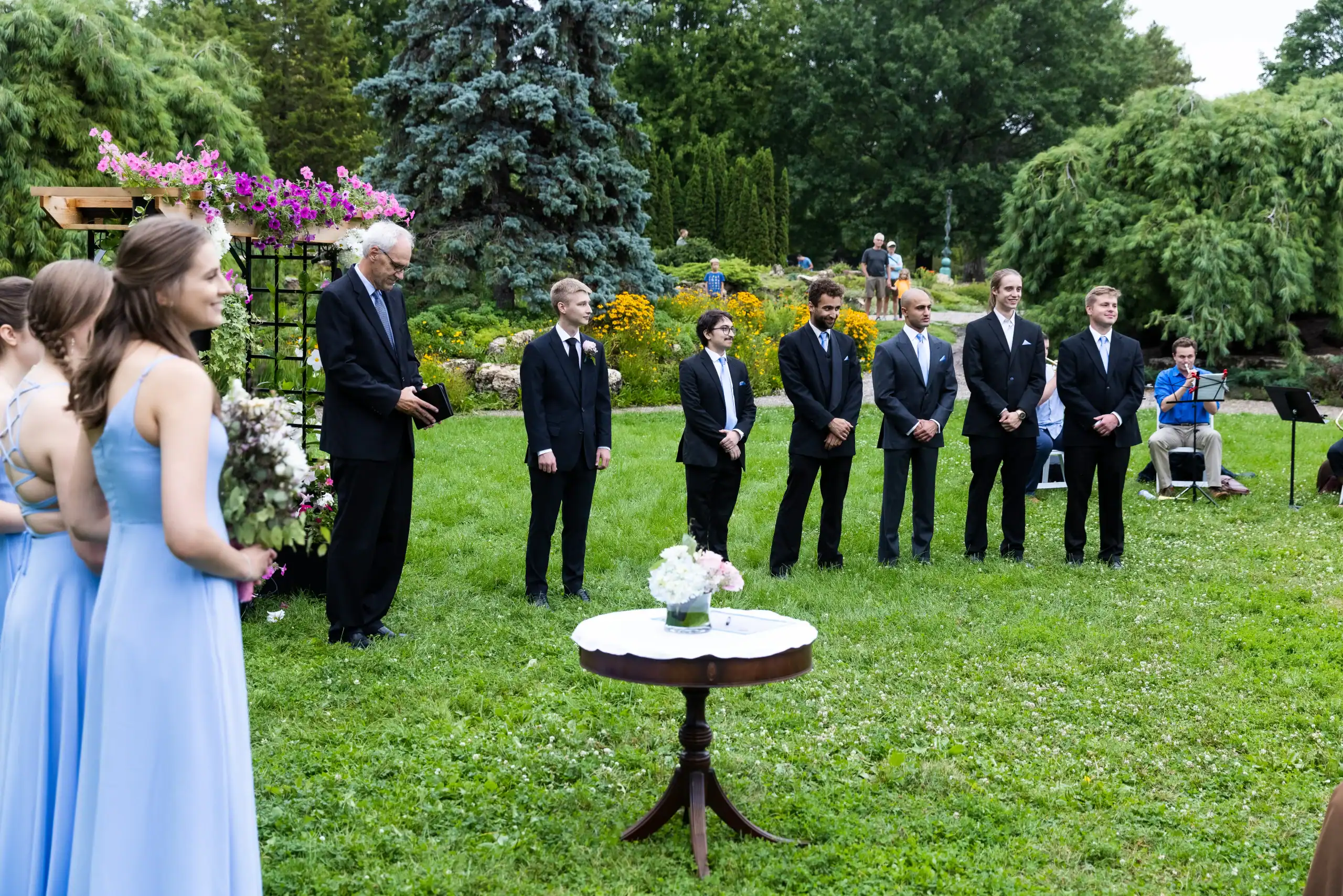 Bridesmaids in blue and groomsmen in suits celebrate at a garden wedding with a top DJ in Minnesota.