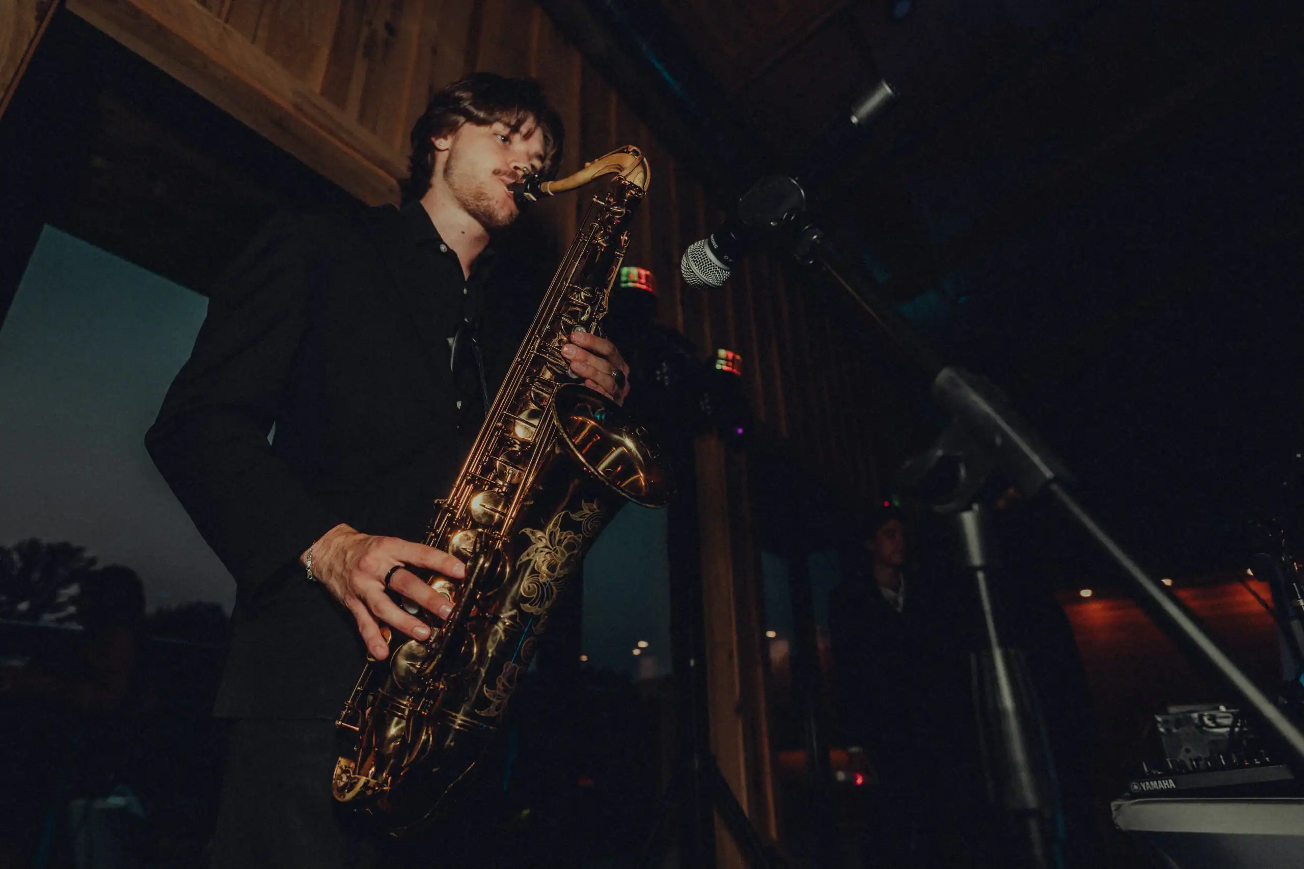 A man in a dark suit plays saxophone on stage, ideal live entertainment for Minnesota weddings.