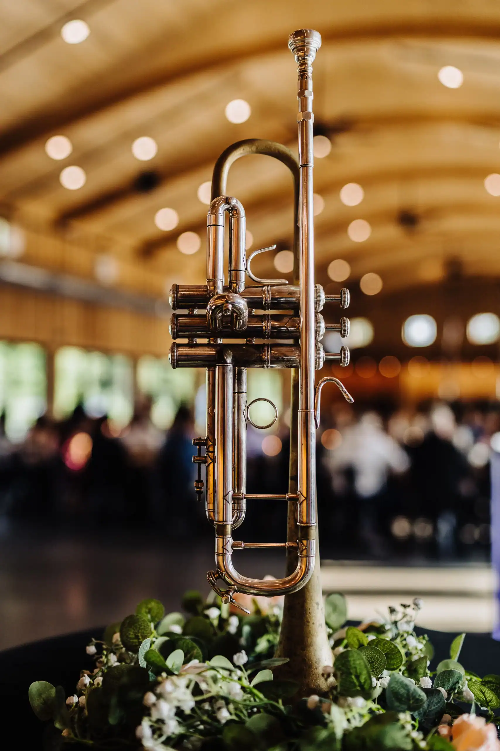 A silver trumpet stands upright on a table in soft indoor light, styled by a wedding DJ Minnesota.