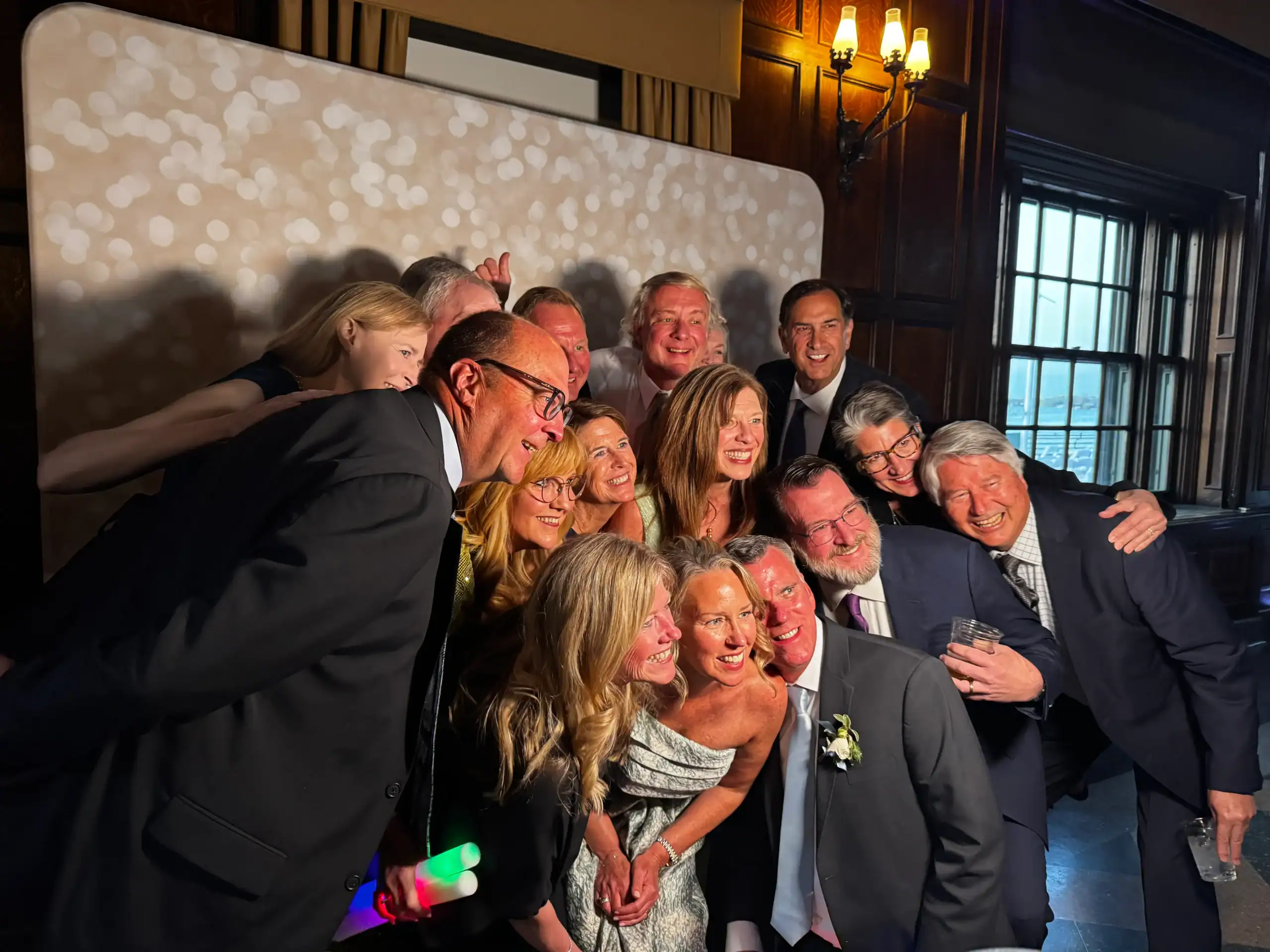 A group of people dressed up, smiling and posing at an indoor event with warm lighting for a photo.